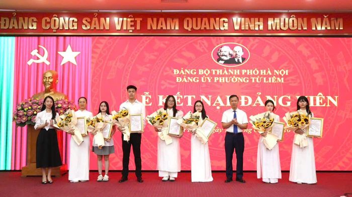 Đồng chí Phó Bí thư Thường trực Đảng ủy phường Đỗ Khắc Đạo trao quyết định kết nạp Đảng và tặng hoa cho các đảng viên mới. Ảnh: PV