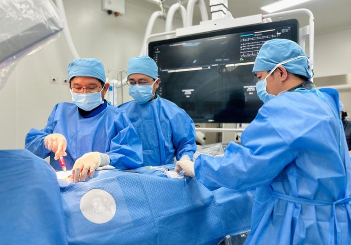 TS.BS Đỗ Nguyên Tín cùng ê-kíp thực hiện thông van tim cho một bệnh nhi. Ảnh: THẢO PHƯƠNG
