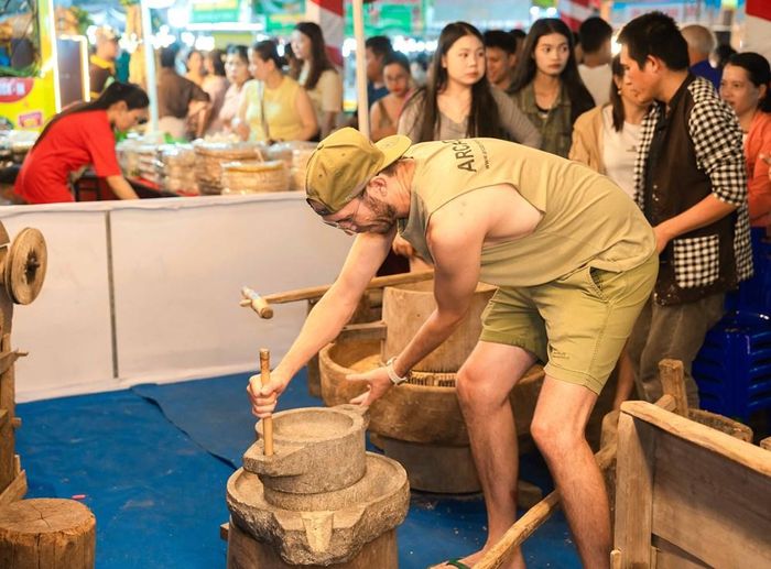 Khách nước ngoài trải nghiệm hoạt động với cối xay bột truyền thống