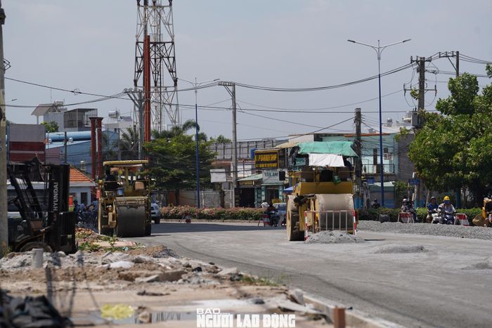 Tại đoạn từ cổng chào Vĩnh Phú đến cầu Ông Bố, công nhân cùng máy móc vẫn đang tất bật hoàn thiện các hạng mục nền đường, bó vỉa và hạ tầng phụ trợ.