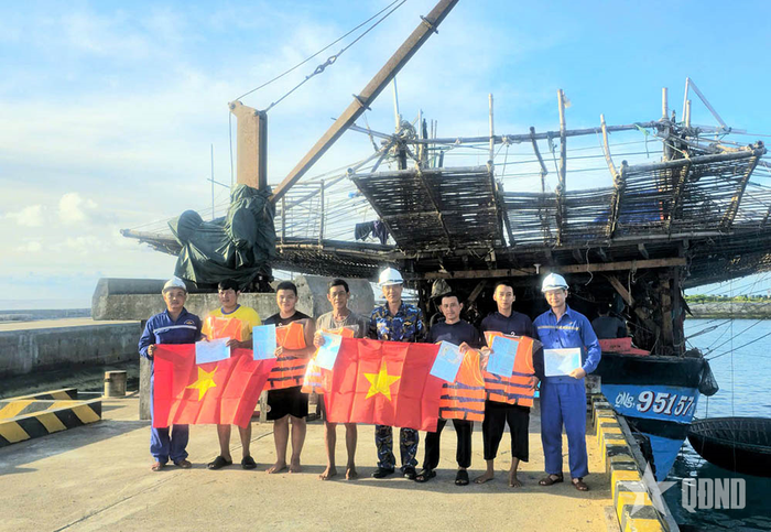 Đại diện đơn vị tặng cờ, áo phao, phát tài liệu tờ rơi tuyên truyền cho ngư dân trên tàu.