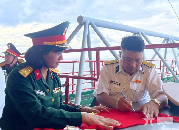 Trung tá Nguyễn Hoàng Vẹn, Chỉ huy trưởng nhà giàn DK-I/9 ký tặng trên khăn thêu cờ Tổ quốc. Ảnh: ANH TUẤN