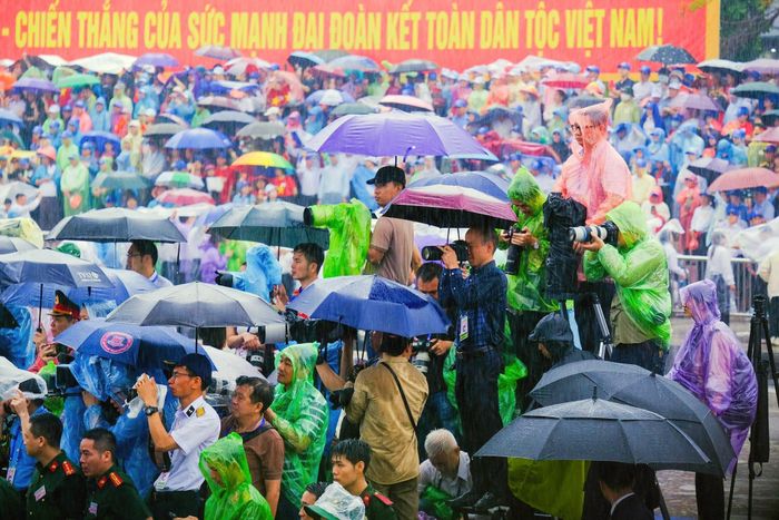 Các nhà báo tác nghiệp sự kiện dưới mưa. Ảnh: Nam Nguyễn