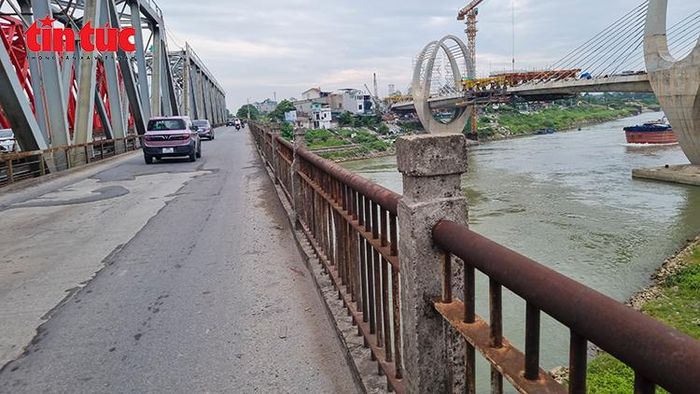 Lan can cầu Đuống cũ hoen gỉ, xuống cấp sau hơn một thế kỷ khai thác, đối lập với diện mạo hiện đại của cầu Đuống mới đang xây dựng phía hạ lưu.