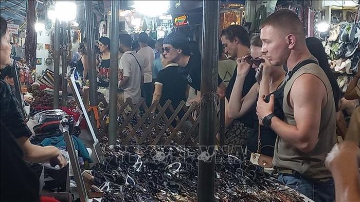 Khách quốc tế yêu thích việc mua sắm quà lưu niệm tại chợ đêm phố cổ Hà Nội. Ảnh: Tuyết Mai/TTXVN