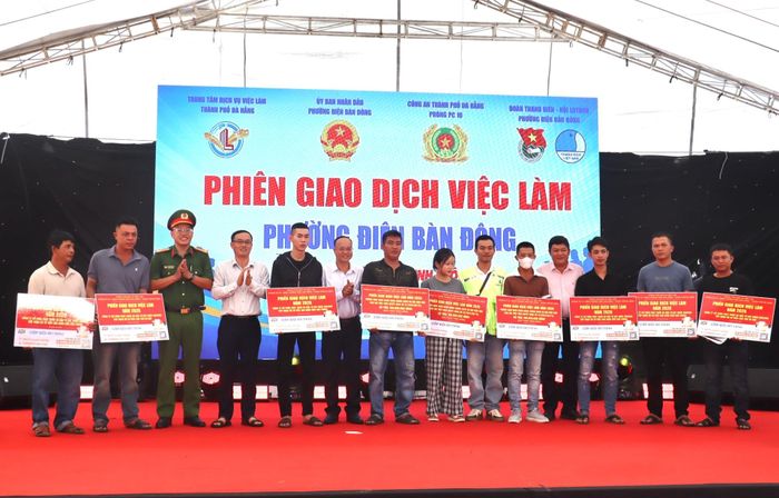 Trao biểu trưng hỗ trợ vốn vay chính sách và tiếp nhận hồ sơ việc làm đối với người lao động tại phiên giao dịch. Ảnh: QUỐC TUẤN