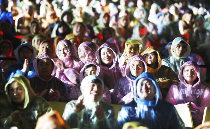 Du khách đội mưa coi show diễn thực cảnh "Ký ức Hội An". Ảnh: ĐẮC MẠNH