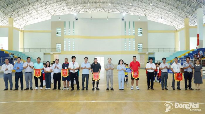 Ông Cao Quốc Sang, Phó Giám đốc phụ trách Báo và Phát thanh, Truyền hình Đồng Nai, Trưởng ban tổ chức giải và bà Nguyễn Thị Cát Tiên, Bí thư Đảng ủy, Chủ tịch HĐND phường Xuân Lộc cùng các đại biểu tặng cờ lưu niệm cho các đội bóng tham gia vòng loại cụm 4. Ảnh: Huy Anh