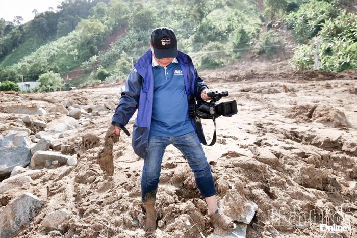 Tác nghiệp tại khu vực bị sạt lở ở Phước Bình, nơi mỗi bước chân đều lún sâu trong bùn đất sau thiên tai.