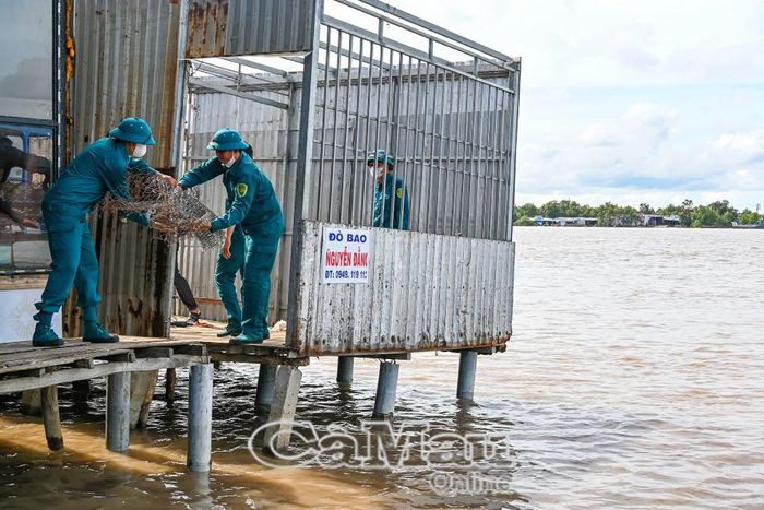 Lực lượng dân quân tự vệ địa phương hỗ trợ bà Nguyễn Thị Hận dọn dẹp, khắc phục thiệt hại sau vụ sạt lở.