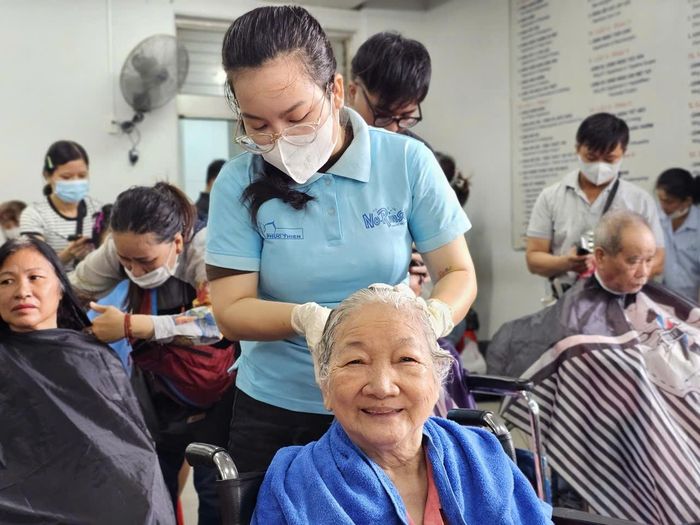 Bà Năm vừa nghe ca nhạc vừa được gội đầu. Ảnh: Nguyễn Thuận.