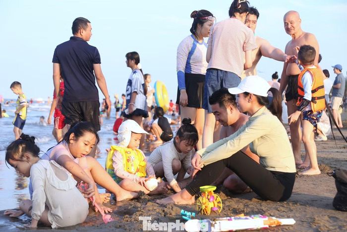 Trên bãi cát, trẻ em thích thú vui đùa cùng bố mẹ.