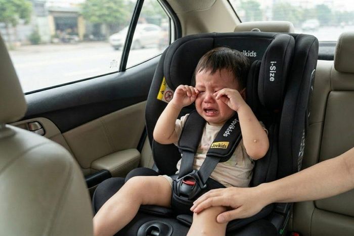 Nhiều trẻ nhỏ thường quấy khóc, đòi được bế hoặc tự ý tháo dây đai khi cảm thấy khó chịu, khiến cha mẹ vừa mất tập trung khi lái xe vừa khó đảm bảo các quy tắc an toàn. Ảnh tạo bởi AI