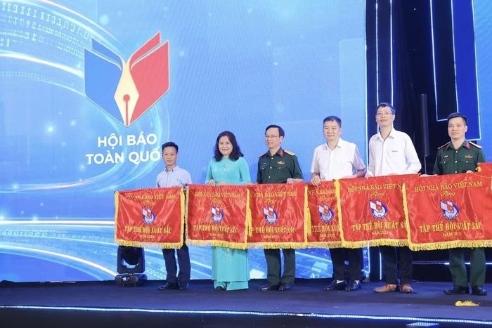 Phó Tổng Giám đốc Thông tấn xã Việt Nam Nguyễn Thị Sự (thứ hai từ trái sang) nhận Cờ thi đua và Bằng khen của Hội Nhà báo Việt Nam cho các đơn vị, cá nhân xuất sắc. (Ảnh: Minh Quyết/TTXVN)