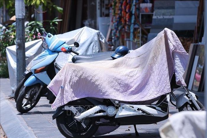 Nhiều chủ xe che chắn xe máy khi nhiệt độ ngoài trời của Hà Nội vượt ngưỡng 40 độ C.