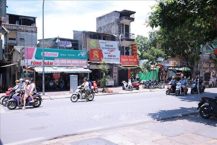 Giữa nền nhiệt ngoài trời vượt 40 độ C, nhiều người dân lựa chọn đứng dưới bóng cây, bóng râm ven đường để tránh nắng trong thời gian chờ đèn đỏ.