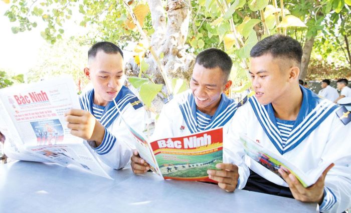  Chiến sĩ đảo Song Tử Tây đọc báo Bắc Ninh dưới tán cây xanh. 