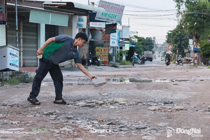 Người dân lấy đá vá ổ gà trên đường Nguyễn Thái Học xuống cấp. Ảnh: Công Nghĩa