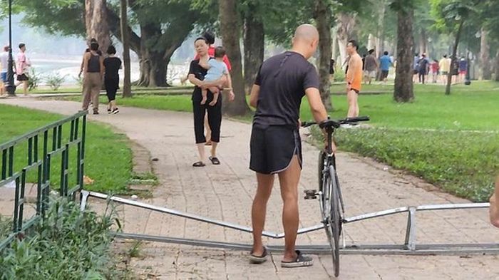 Một người đi xe đạp nhấc xe qua lối đi đã chắn ngang. Ảnh: VA.