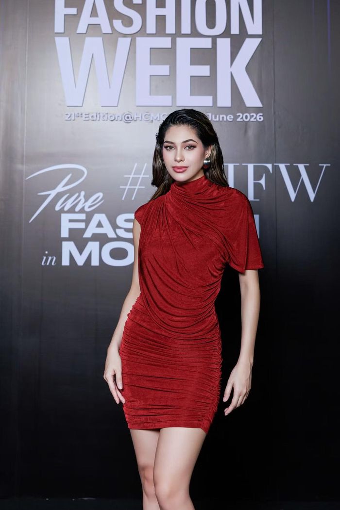 Đương kim Á hậu Miss Cosmo Chelsea Fernandez diện đầm ngắn màu đỏ rượu vang với phom ôm sát. Thiết kế cổ cao, bất đối xứng ở phần tay áo và được xử lý nhún vải toàn bộ thân váy.