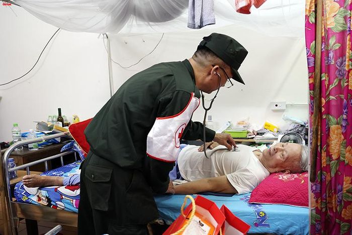 Bác sĩ quân y thăm khám tại giường cho thương binh sức khỏe yếu.