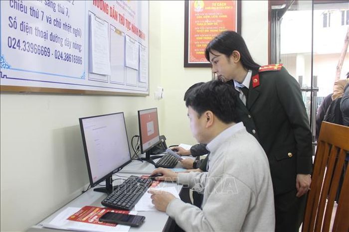 Cán bộ Công an thành phố Hà Nội hướng dẫn người dân thực hiện các thao tác giải quyết thủ tục cấp Phiếu lý lịch tư pháp. Ảnh: Nguyễn Thắng/TTXVN