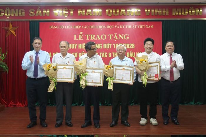 Đồng chí Châu Văn Minh và đồng chí Nguyễn Phi Long trao huy hiệu Đảng cho các đảng viên. Ảnh: Mai Loan