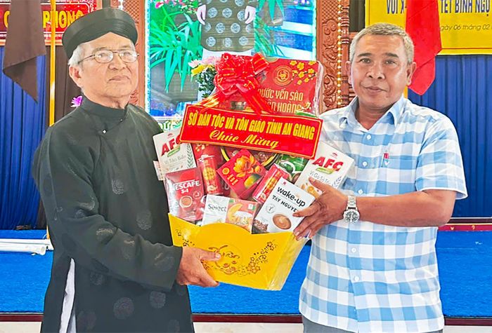 Phó Giám đốc Sở Dân tộc và Tôn giáo tỉnh An Giang Danh Lắm tặng quà ông Trương Văn Điệp, Trưởng ban Trị sự Phật giáo Hòa Hảo xã Châu Phong.
