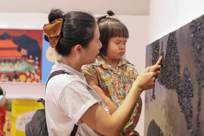 Các em nhỏ nhắm mắt, chạm vào tranh để hiểu hơn về cách người khuyết tật cảm nhận thế giới. Ảnh: TRUNG ANH