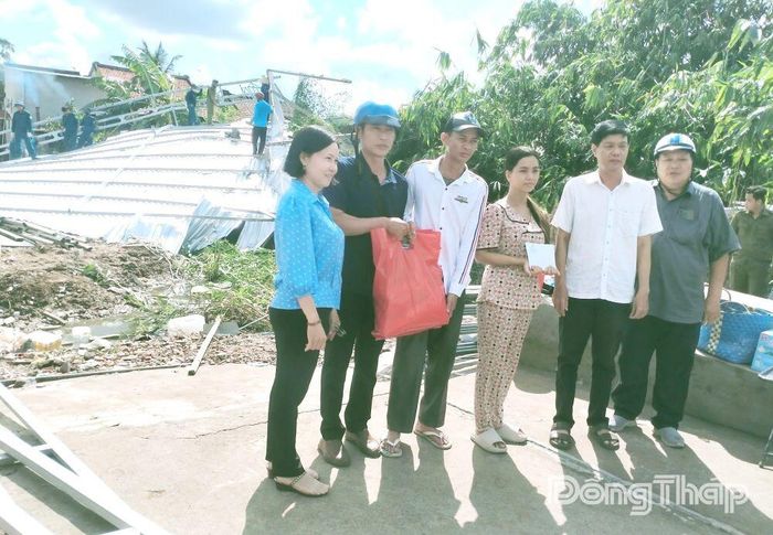 Chủ tịch UBND phường Mỹ Ngãi Nguyễn Hoàng Hơn (thứ 2 từ phải sang) hỗ trợ tiền và quà cho hộ ông Nguyễn Chí Thanh có nhà bị sập hoàn toàn.