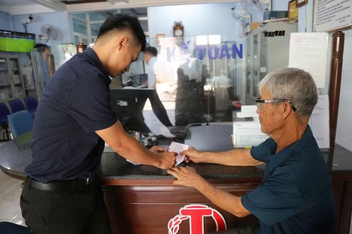 Ông Huỳnh Tấn Thành (bên phải) thực hiện thủ tục gửi tiền tiết kiệm vào Quỹ TDND Bình Dương. Ảnh: T.S