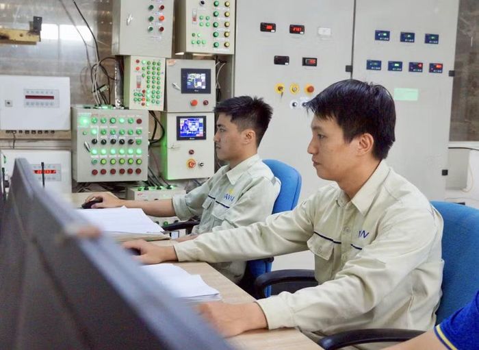 Anh Phan Vũ Hiển (bìa phải) vận hành máy móc thiết bị tại phòng làm việc. Ảnh: N.M
