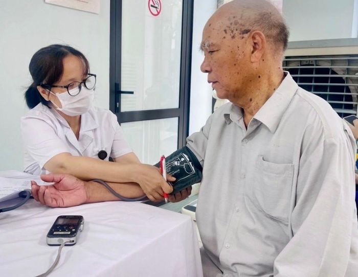 Nhân viên y tế đo huyết áp cho ông Công Phương Nhị, người có công ở tổ dân phố số 6, phường Phú Thượng. Ảnh: Tuệ Lâm