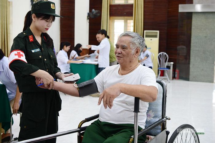 Cán bộ quân y đo huyết áp, kiểm tra sức khỏe ban đầu cho thương binh.