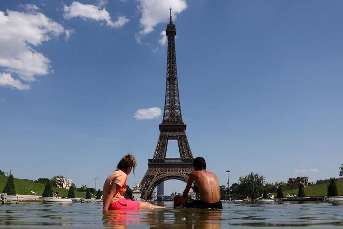 Người dân giải nhiệt tại Đài phun nước Trocadero cạnh Tháp Eiffel ở Paris khi nhiệt độ tăng cao trong đợt nắng nóng ảnh hưởng đến phần lớn nước Pháp. Nguồn: Reuters.