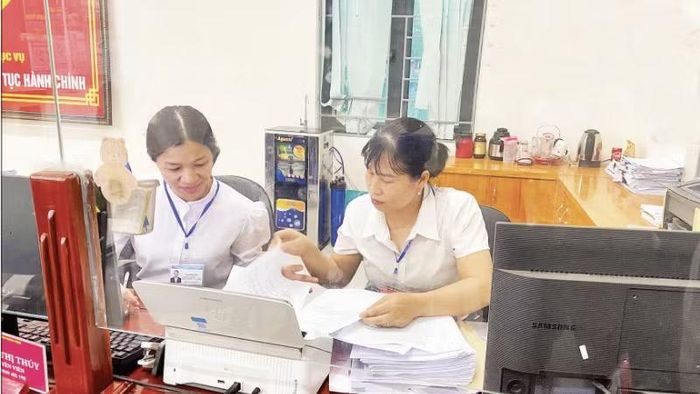 Đồng chí Phạm Thị Thúy (bên phải) cùng đồng nghiệp ở lại sau giờ làm việc tiếp tục nghiên cứu hồ sơ giúp nhân dân hoàn thành các thủ tục hành chính tại Trung tâm Phục vụ hành chính công.