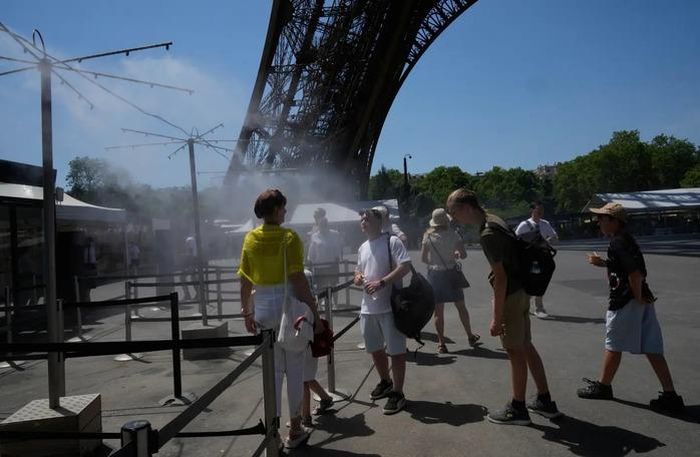 Người dân giải nhiệt dưới làn nước phun tại thủ đô Paris - Pháp hôm 21-6. Ảnh: AP