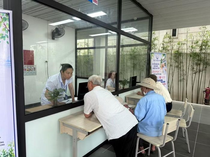 Nhân viên y tế của Trung tâm hướng dẫn người cao tuổi làm các thủ tục. (Ảnh: Thùy Giang/Vietnam+)