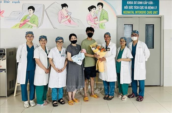 Nhân viên y tế Bệnh viện Phụ sản - Nhi Đà Nẵng tặng hoa chúc mừng vợ chồng và em bé được xuất viện. Ảnh: TTXVN phát