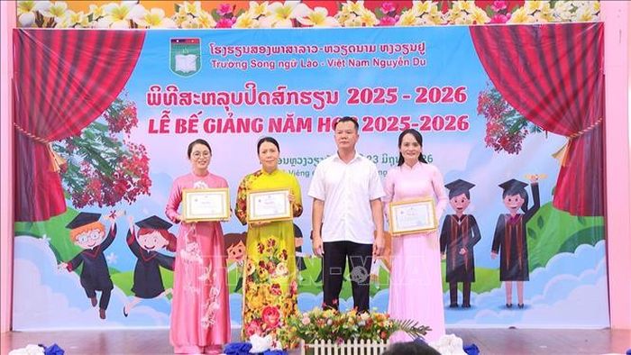 Ban giám hiệu nhà trường nhận bằng khen của Thành hội Hội người Việt Nam Thủ đô Vientiane. Ảnh: Xuân Tú/PV TTXVN tại Lào
