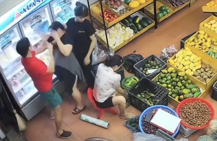 Người đàn ông mặc áo đỏ tác động liên tiếp vào vùng mặt người phụ nữ mặc váy tối màu tại một cửa hàng bán hoa quả thuộc phường Quế Võ, tỉnh Bắc Ninh. Ảnh cắt từ clip