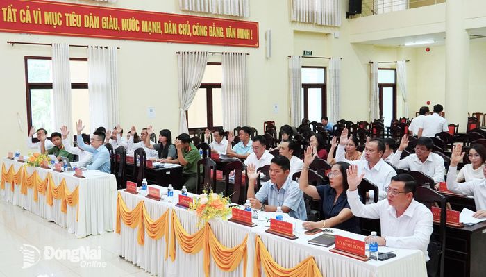 Các đại biểu biểu quyết thông qua dự thảo Nghị quyết về Đề án sắp xếp, điều chỉnh, đổi tên các khu phố trên địa bàn phường Tân Khai. Ảnh: Thanh Mai