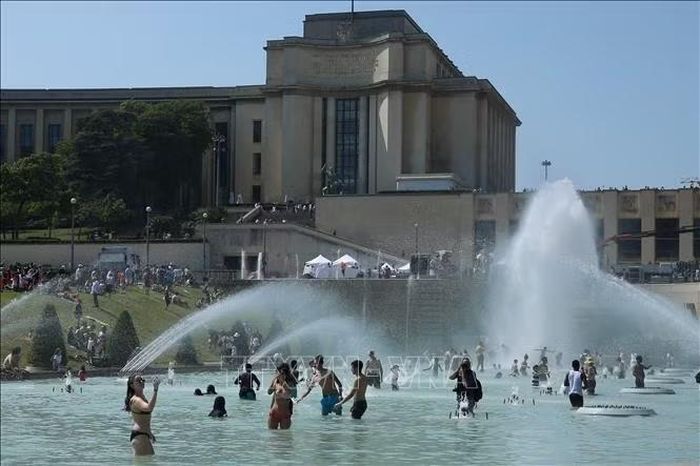 Người dân tránh nóng tại đài phun nước ở Paris, Pháp. Ảnh: THX/TTXVN