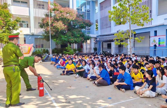 Cán bộ công an phường hướng dẫn học sinh sử dụng bình chữa cháy đúng cách