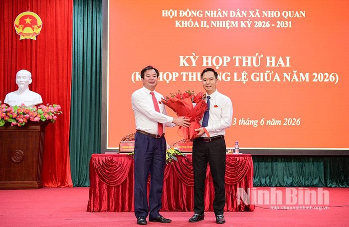 Đồng chí Hoàng Khắc Tiệp, Bí thư Đảng ủy, Chủ tịch HĐND xã tặng hoa chúc mừng đồng chí Phạm Quang Quân được bầu giữ chức Phó Chủ tịch UBND xã Nho Quan. Ảnh: Trường Giang