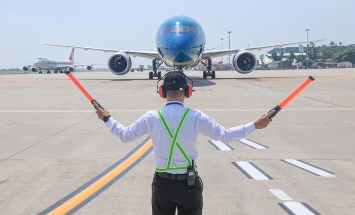 Signalman đánh tín hiệu hướng dẫn tàu bay lăn vào vị trí đỗ.