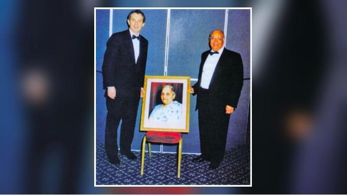 Tại lễ ra mắt Quỹ Loomba ở London năm 1998: Thủ tướng Anh Tony Blair (trái) và Raj Loomba bên chân dung bà Pushpa Wati Loomba. (Ảnh: The Loomba Foundation).