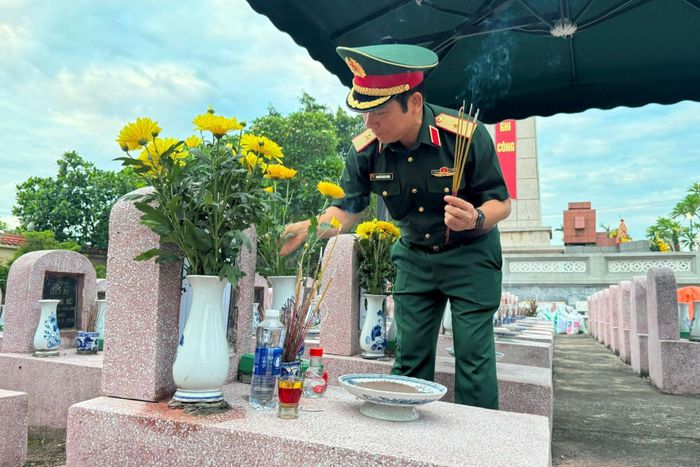 Thiếu tướng Nguyễn Khắc Nhân, Phó Chính ủy Bộ Tư lệnh Thủ đô, Phó trưởng Ban Chỉ đạo thành phố Hà Nội về tìm kiếm, quy tập và xác định danh tính hài cốt liệt sĩ chỉnh hoa, thắp hương trên phần mộ liệt sĩ chưa xác định danh tính. Ảnh: Mai Hoa