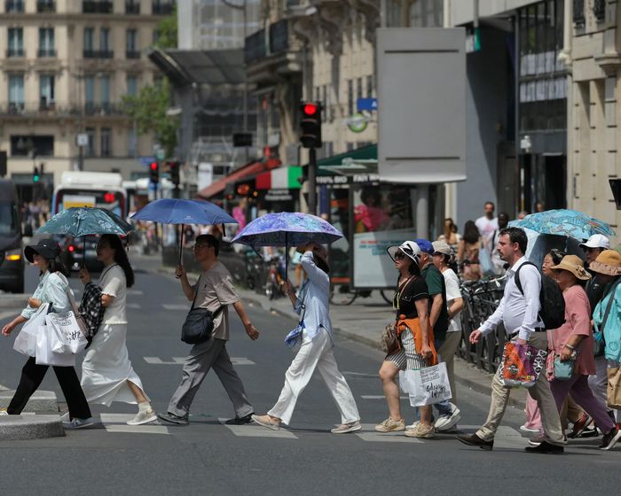 Khách du lịch che chắn nắng nóng, trên đường phố Paris (Pháp) hôm 23-6. Ảnh: AFP