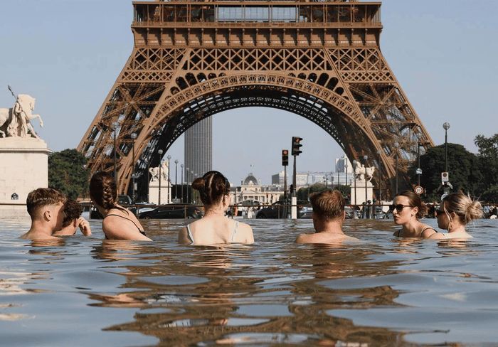 Người dân giải nhiệt tại đài phun nước Trocadéro bên cạnh tháp Eiffel khi nhiệt độ tăng cao ngày 22/6/. Ảnh: Reuters.